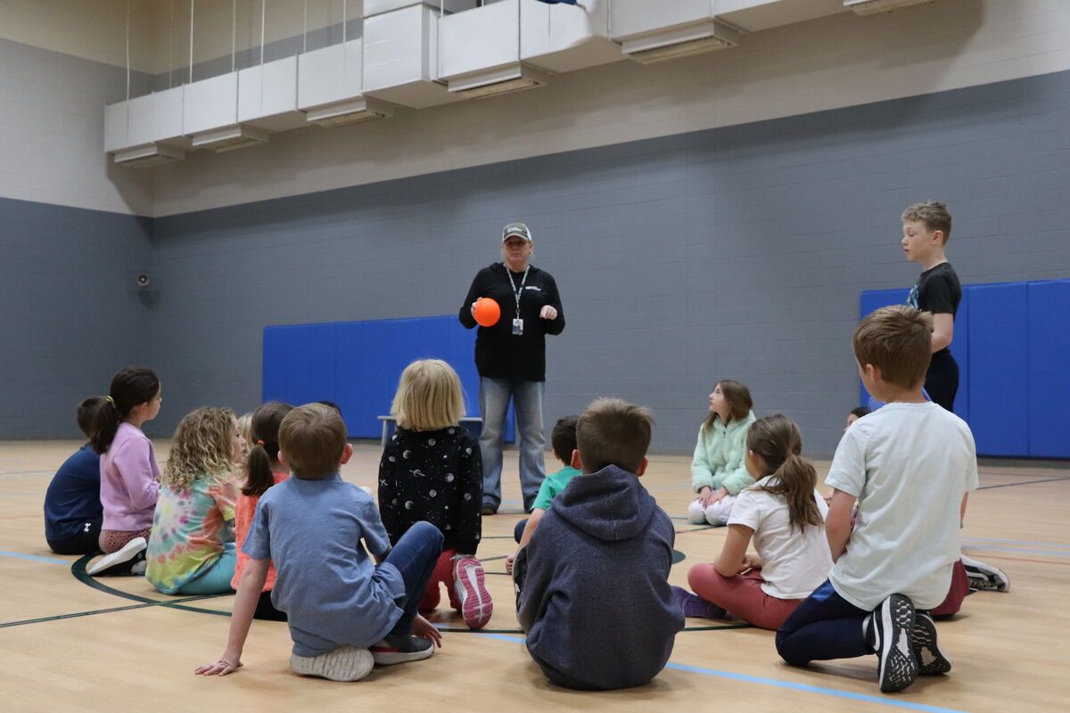 An instructor holding a basketball while children gather around him inside a South Suburban rec center.