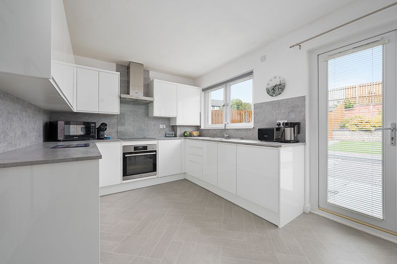 Modern white kitchen with sleek cabinets, built-in appliances, and large windows offering natural light.