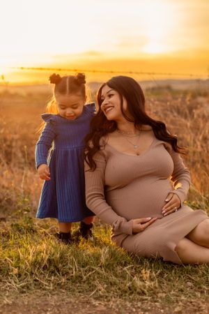 A mother and child share a special moment in a field during golden sunset.