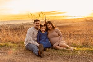 A family sits together on a rural path during golden hour.