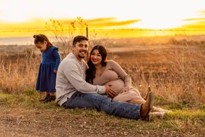 A family enjoys sunset together in a rural field with golden light.