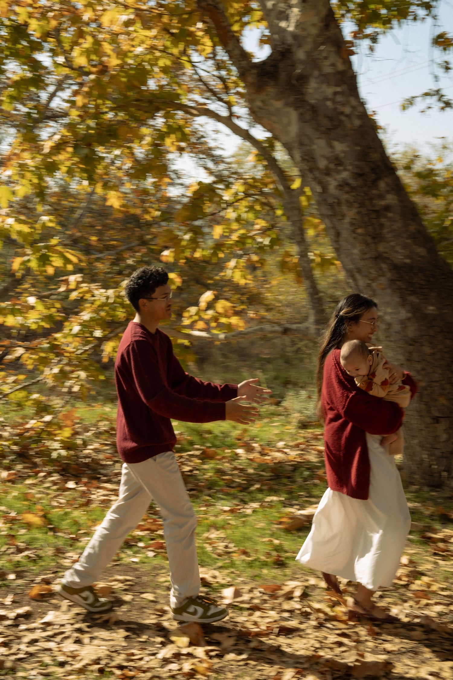 A sequence showing two people in burgundy and white walking through autumn leaves.