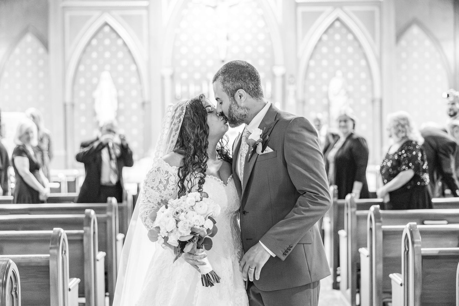 Black and white wedding photos showing tender moments between a couple in a church setting with elegant decor.
