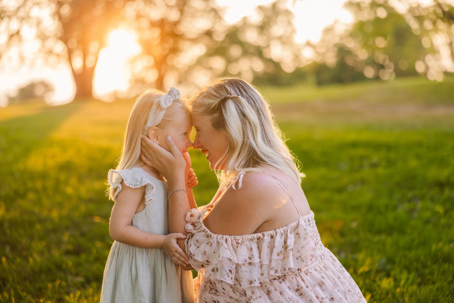 A couple shares a tender moment in a sun-drenched grassy field during golden hour.