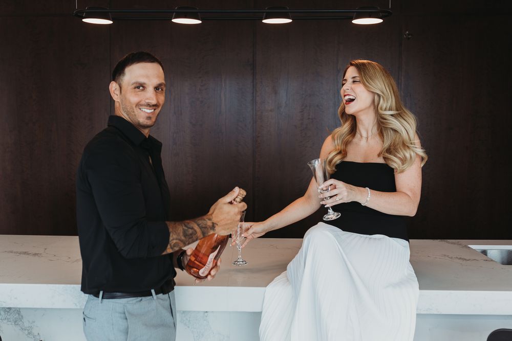 A couple shares champagne toasts and laughter during a romantic evening celebration.
