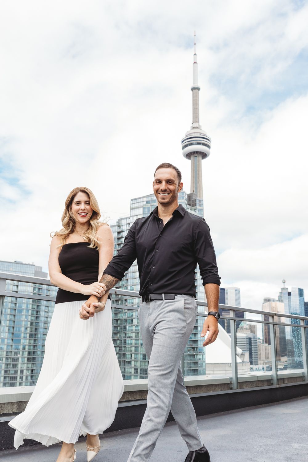 Playful dance moves on a modern high-rise terrace with Toronto's iconic CN Tower visible in background.