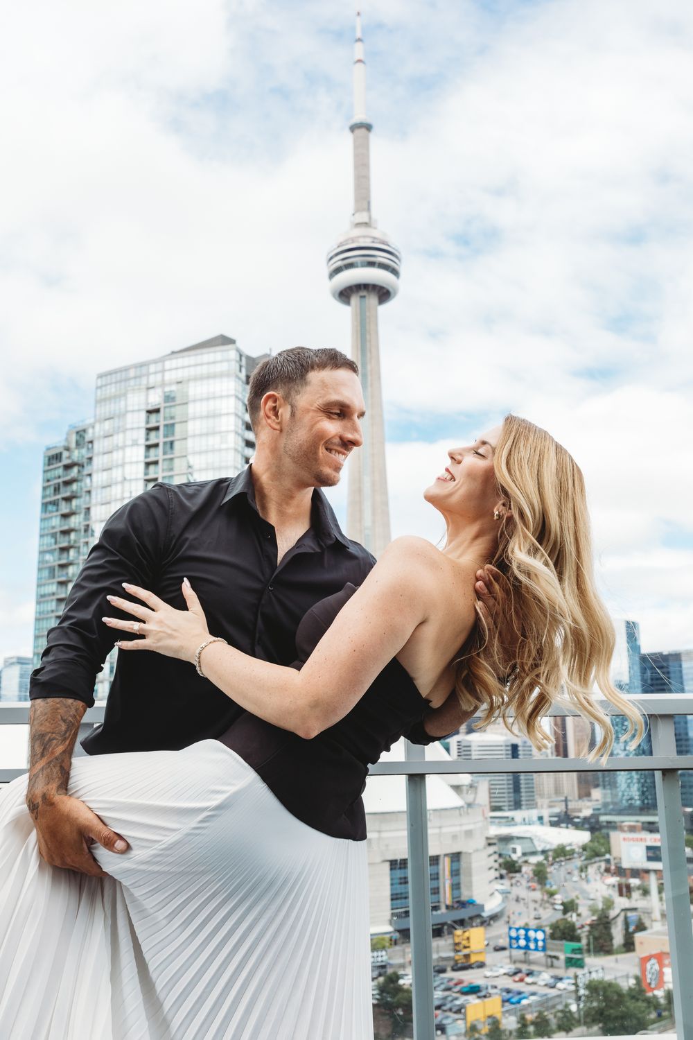 Romantic dance pose on a Toronto rooftop patio with the iconic CN Tower in the background.
