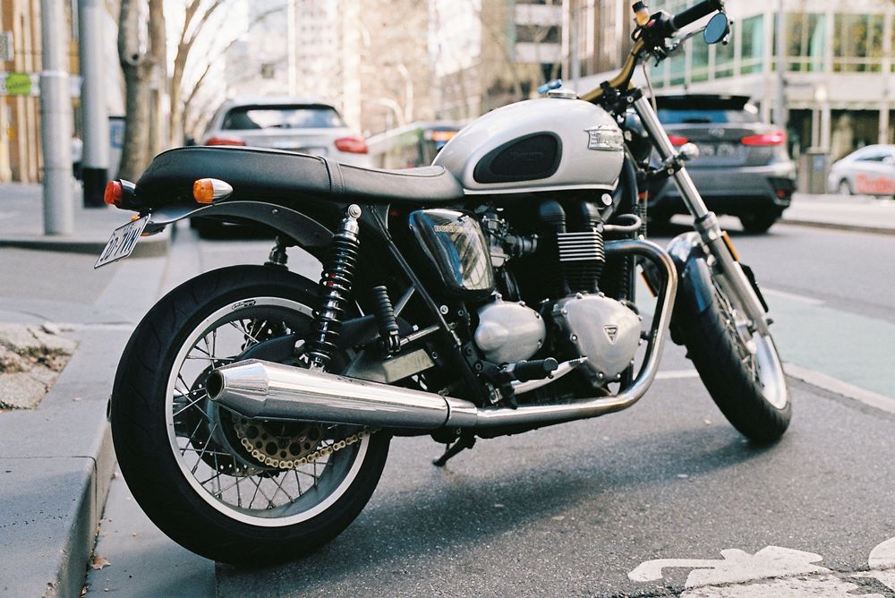 Black motorcycle parked on urban street with classic styling and chrome accents visible in profile view.