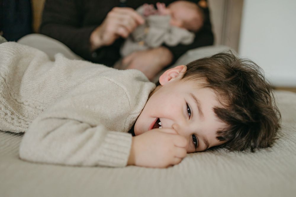A person wearing a cozy cream sweater lies peacefully on white bedding in soft natural light.