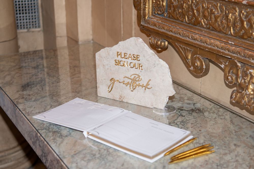White marble guest book station with pencils and elegant signage.