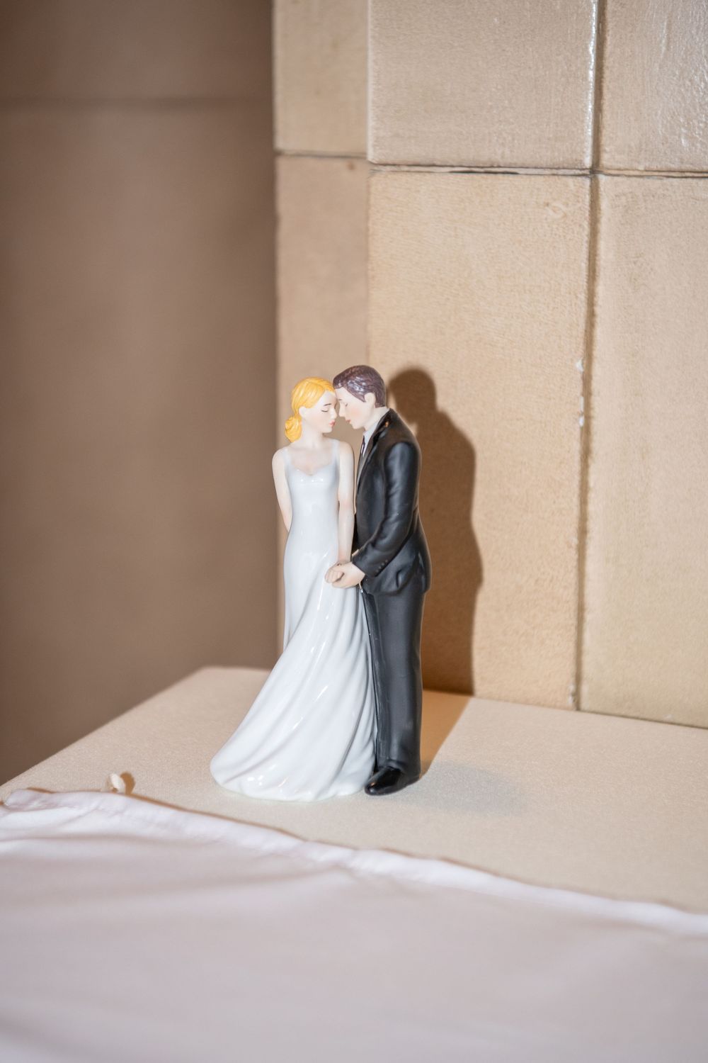 Small decorative wedding cake topper figurine of a couple in formal attire.