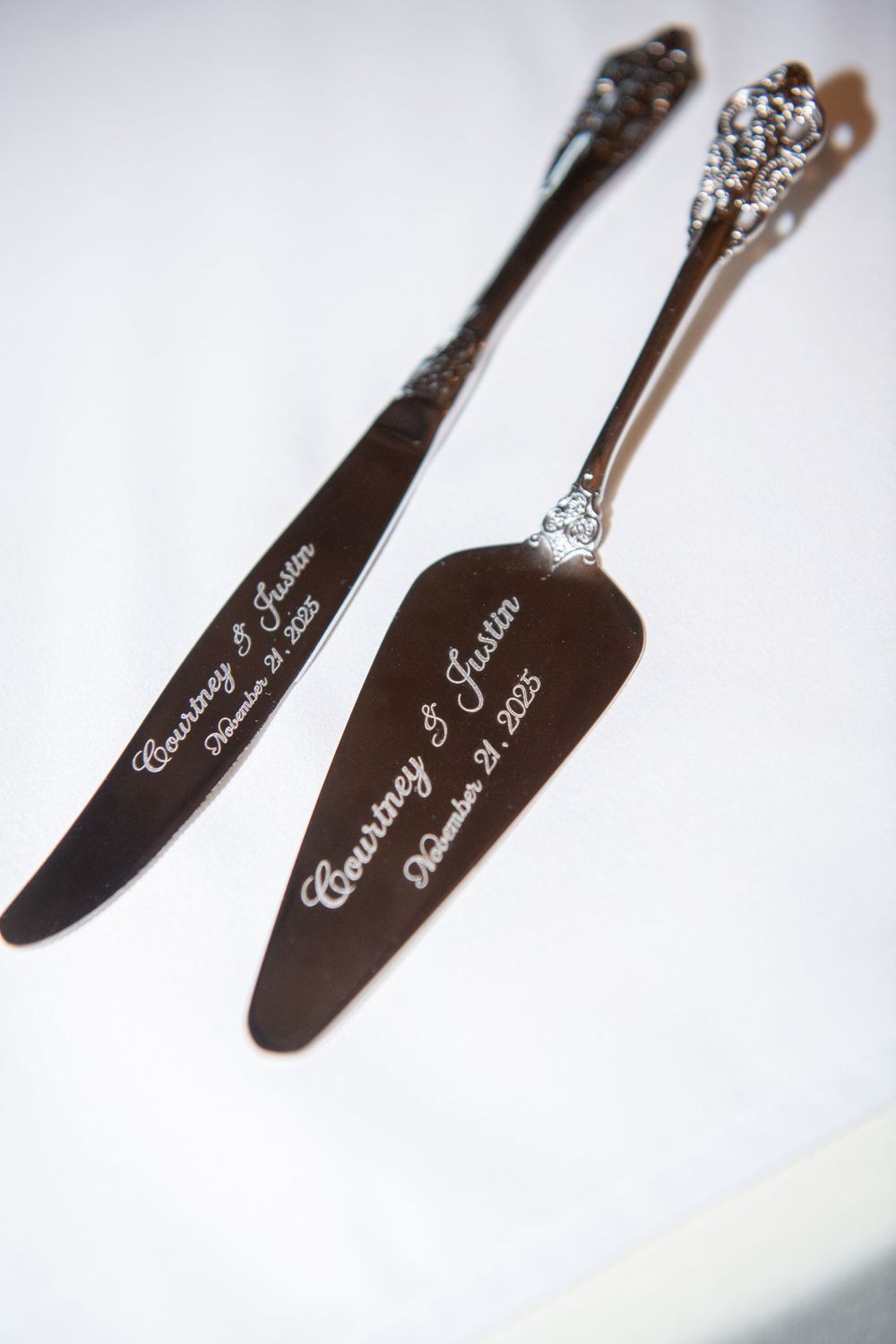 Engraved silver wedding cake serving utensils with ornate handles.