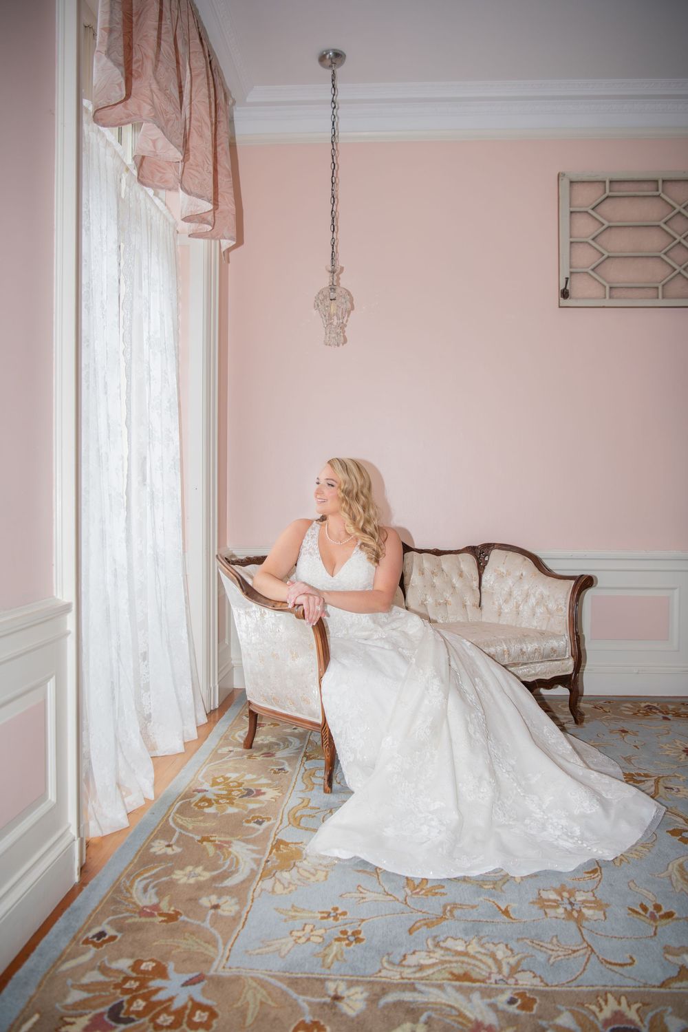 Elegant bridal portrait in a pink room with antique furniture and ornate carpet.