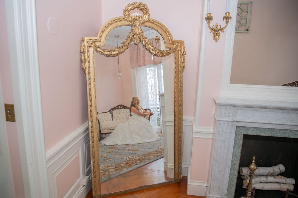 Luxurious bridal room featuring gold-framed mirror and pink walls with classic white molding.