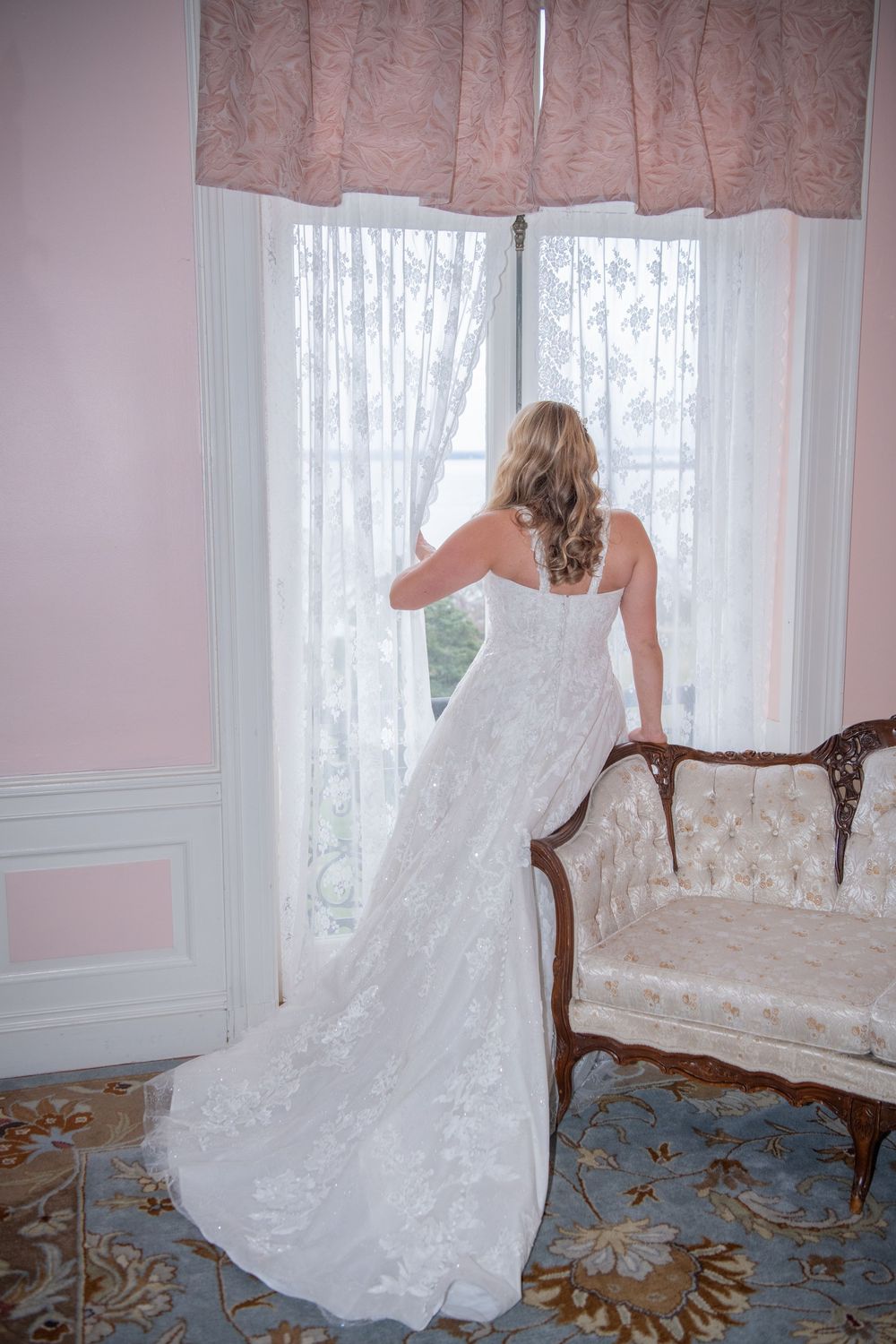 White lace wedding gown flowing dramatically across an antique chaise lounge.