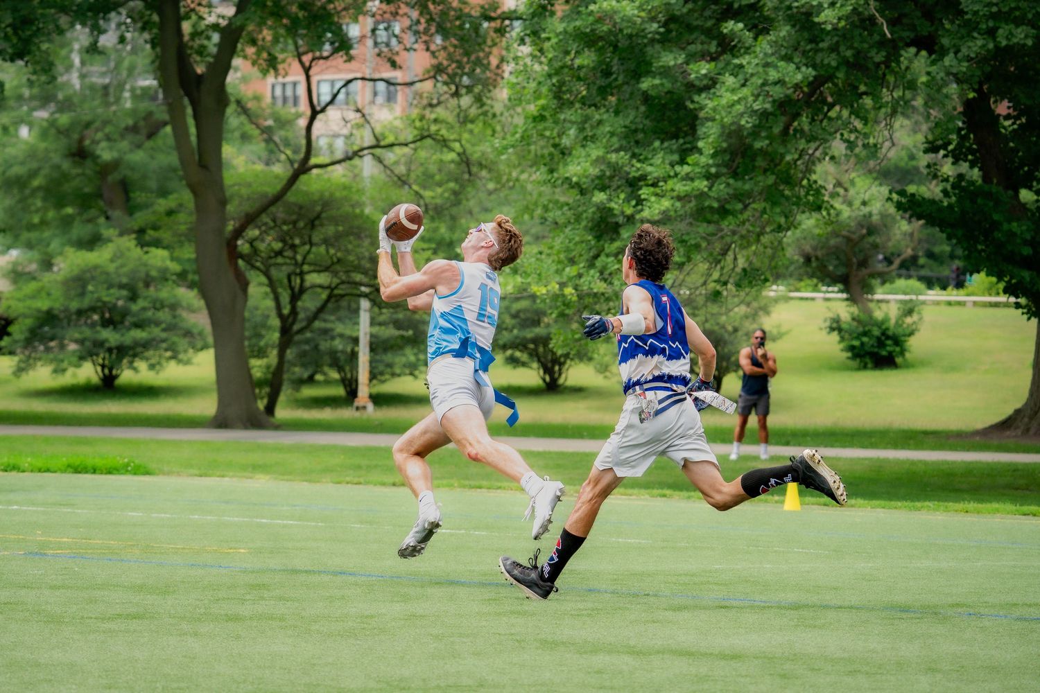 A football player from Chicago Freeze successfully catches a deep ball near the end zone with a defensive player in pursuit