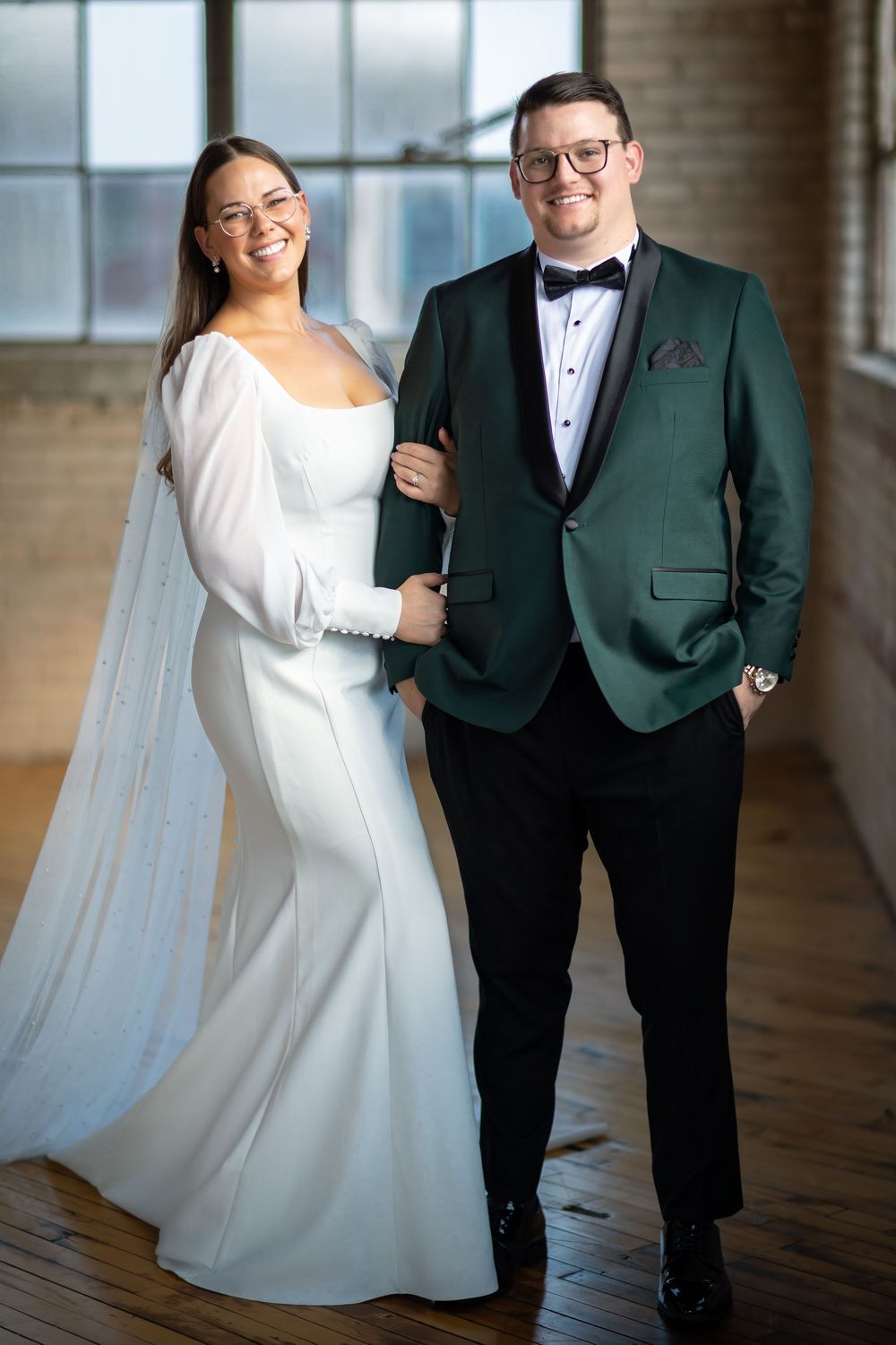 Wedding couple poses in a modern industrial venue with large windows.
