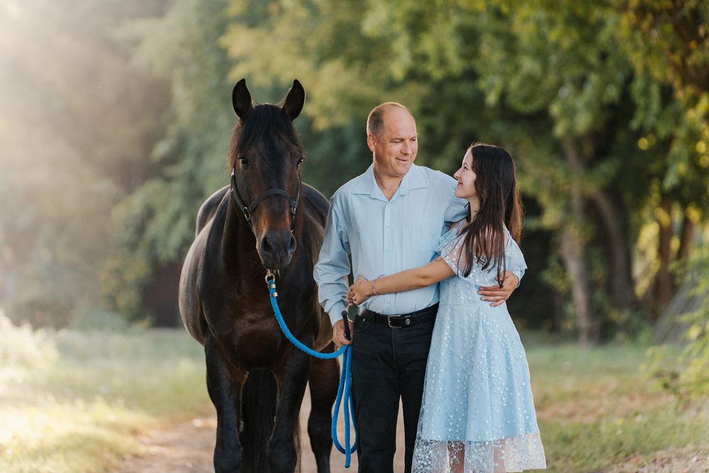 Dad and daughter photoshoot with their black horse in a natural setting in Sydney Hills district