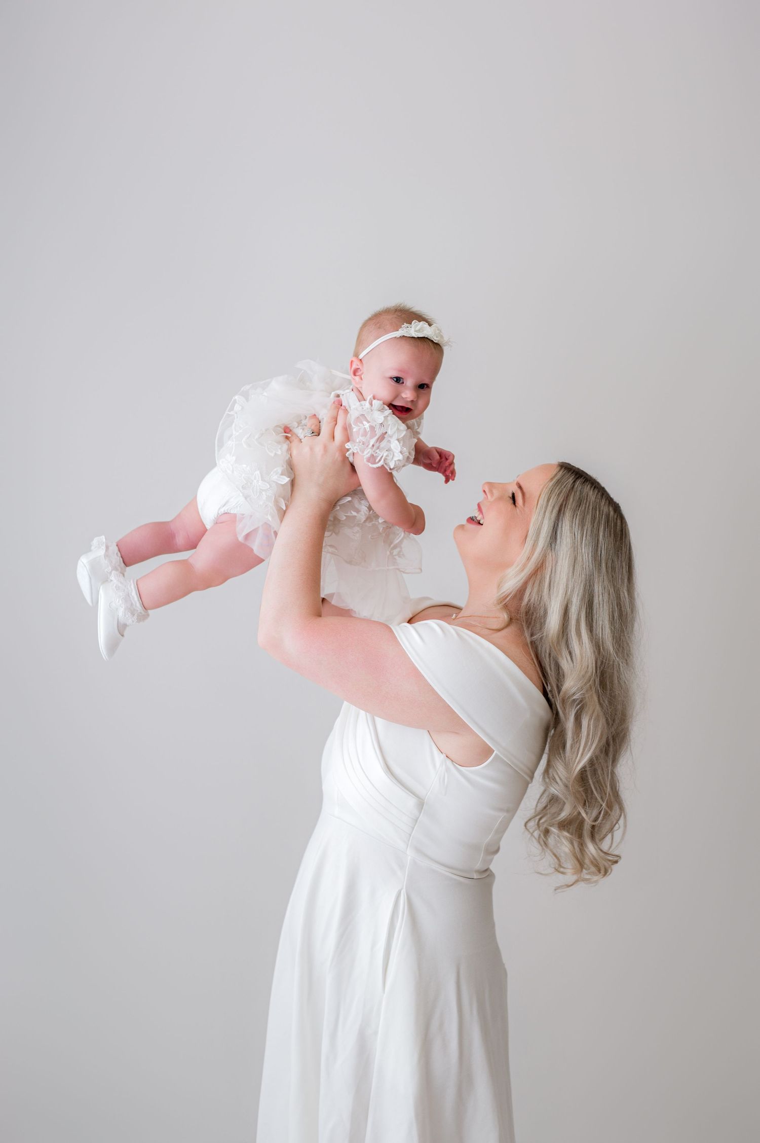 A series of tender moments captured in a minimalist studio setting with a white platform against a light gray background.