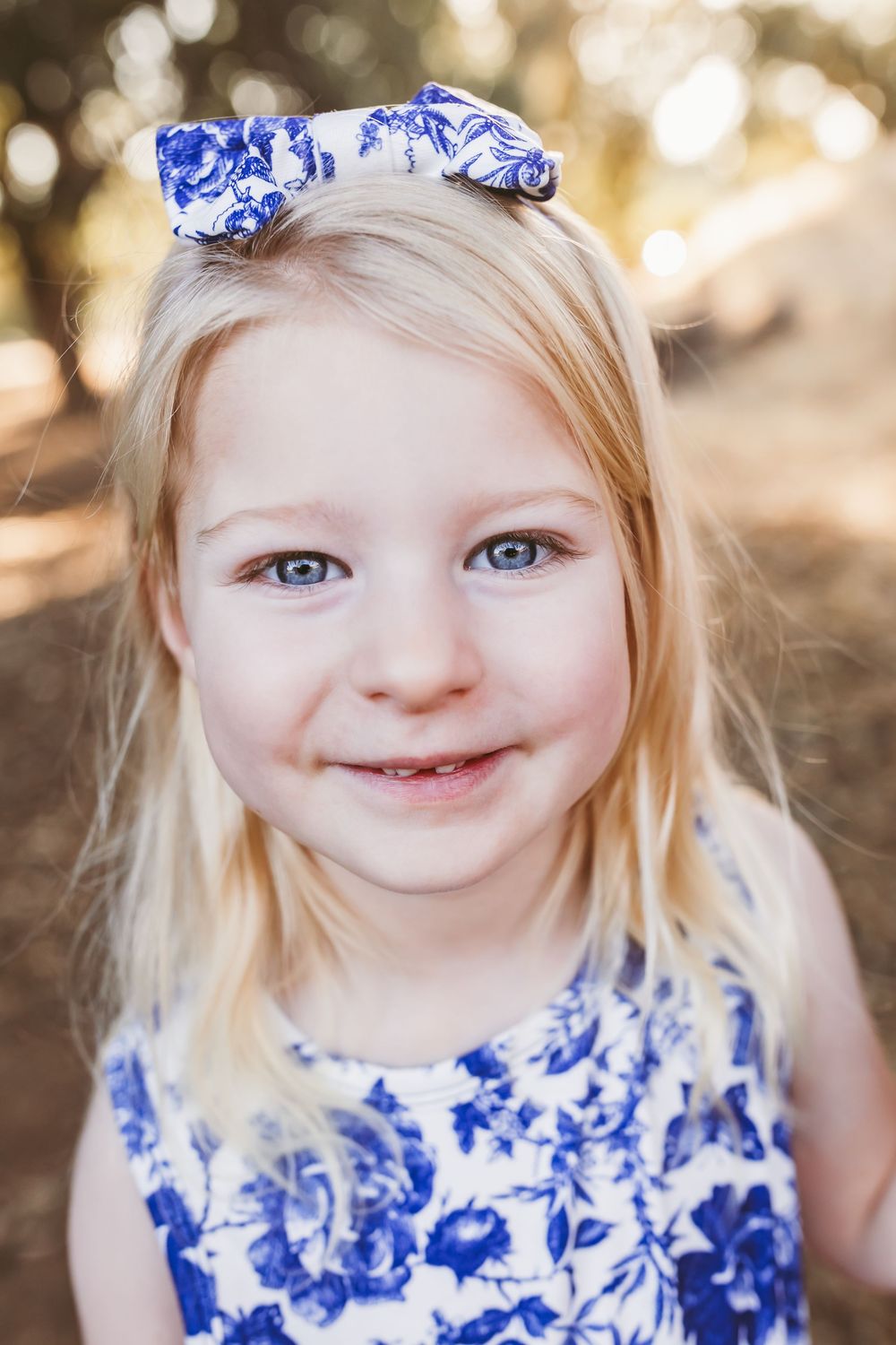 A child in a blue and white floral dress smiles joyfully in a series of outdoor portrait shots.