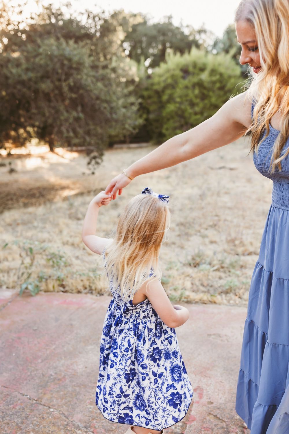 A series of candid moments captured between parent and child wearing coordinating blue dresses outdoors.
