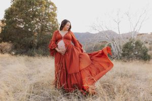 Flowing red dress creates artistic motion in a mountain landscape.