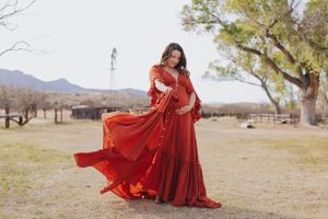 Elegant red dress maternity photos taken in a desert landscape with mountains.