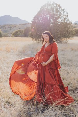 Sunlit desert maternity session featuring dramatic red dress movement.