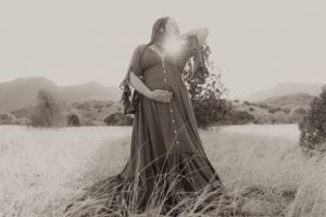 Black and white portrait of a flowing dress in a serene mountain field setting.