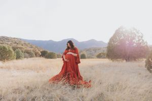 Dreamy sunset photography session featuring a red dress in a mountain meadow.
