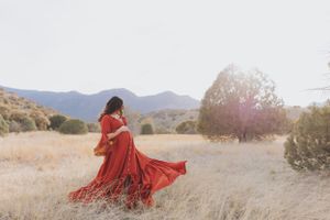 Artistic portrait session in a golden field with mountains and natural lighting.