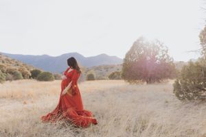 Elegant red dress photoshoot against a mountainous desert landscape.