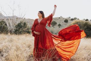 Vibrant red fabric billows dramatically in the wind across a desert landscape.