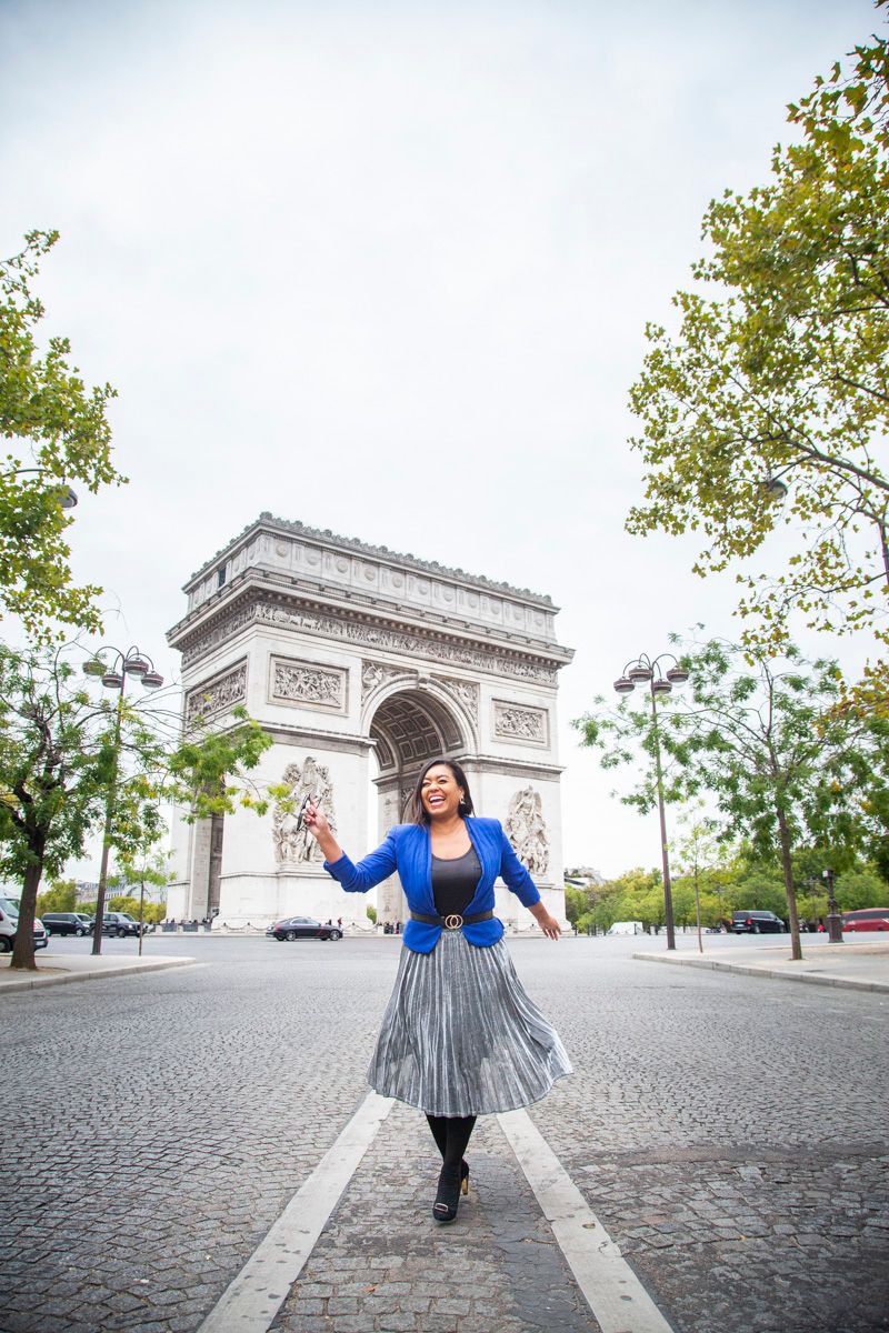 A joyful scene in front of the Arc de Triomphe in Paris with the iconic monument and cobblestone street in view.