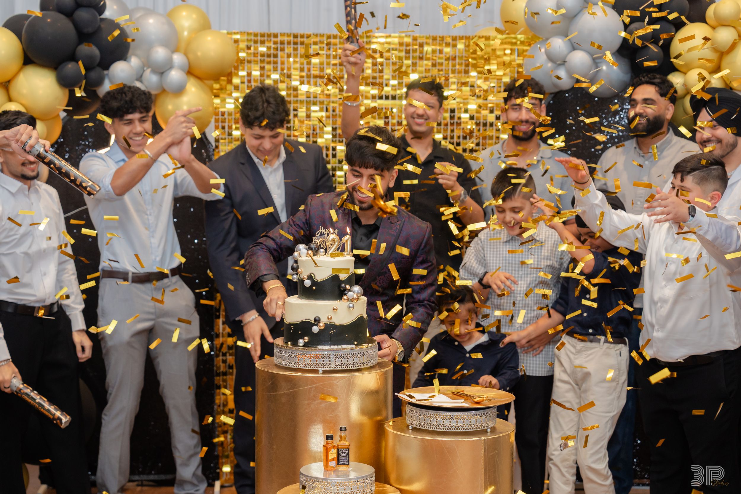 Wedding celebration with gold and white balloons, confetti, and guests celebrating in a festive party atmosphere.