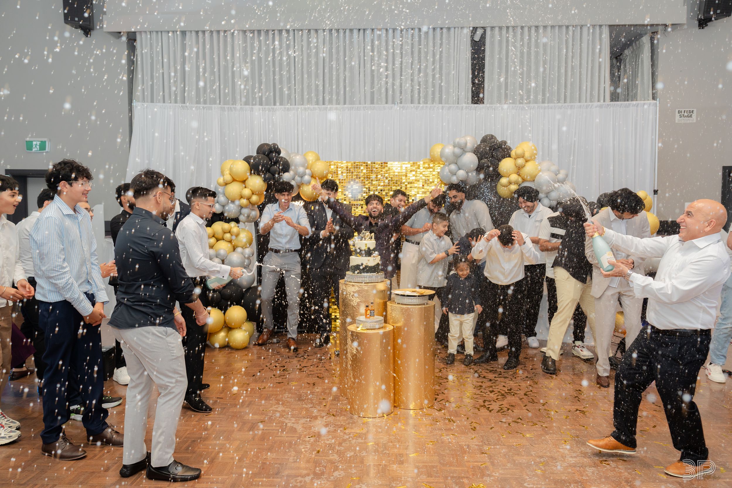 Wedding reception venue decorated with silver and gold accents showing guests celebrating with confetti.