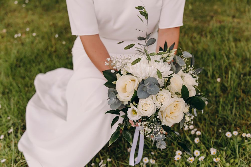 White roses and delicate floral arrangements adorn an elegant outdoor wedding ceremony setting.