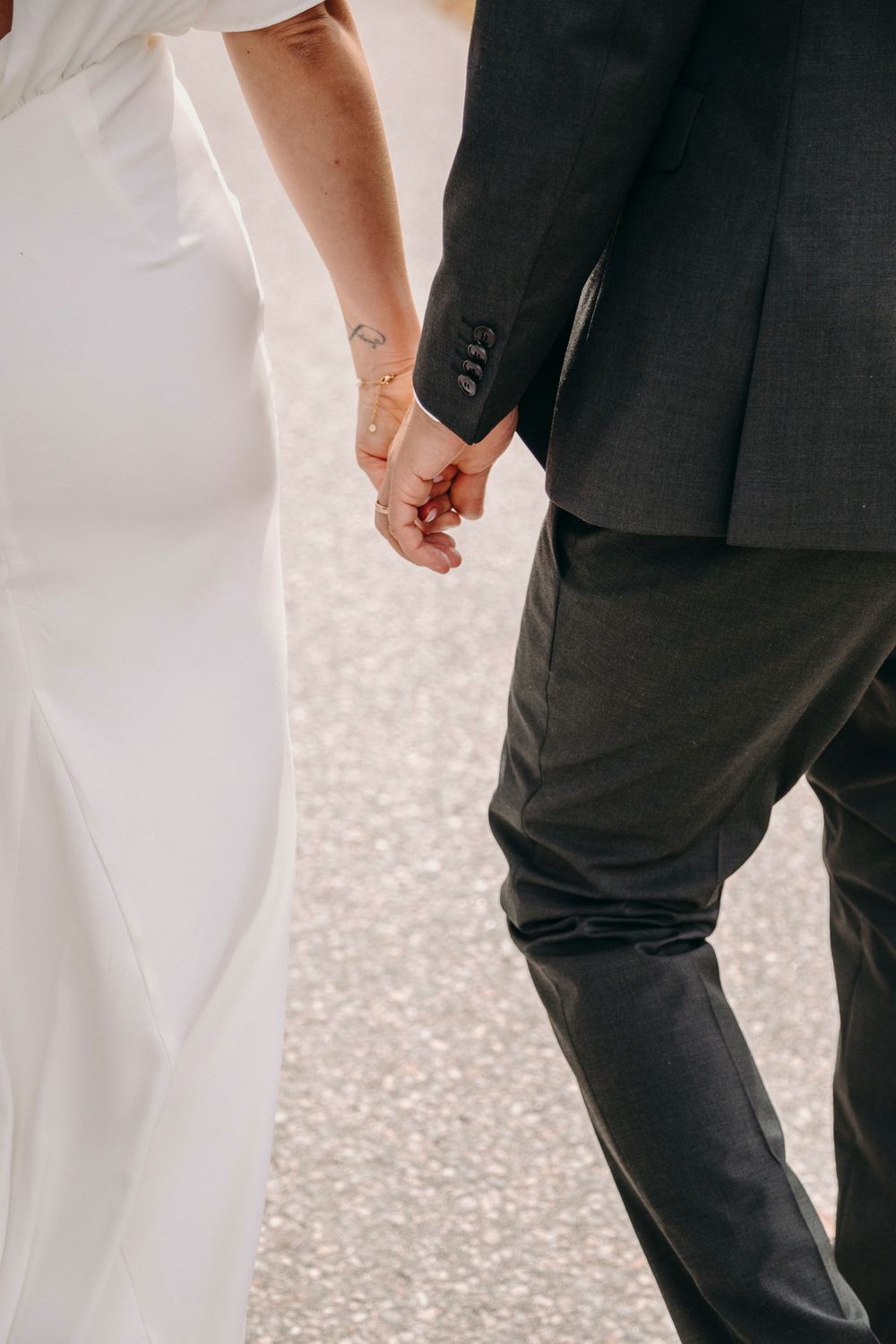 Close-up view of a bride and groom holding hands during their wedding ceremony with sparkly bokeh background.
