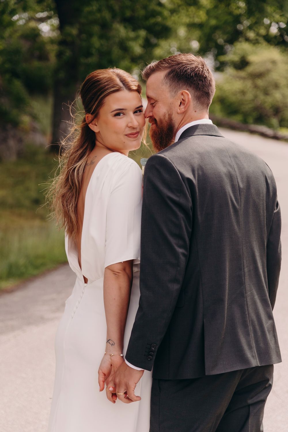 A romantic wedding couple holds hands and shares intimate moments on a sunlit path in a series of candid photos.