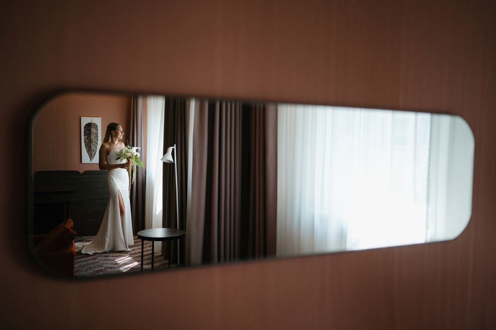 Wedding dress reflection captured in long mirror showing elegant bridal preparation.