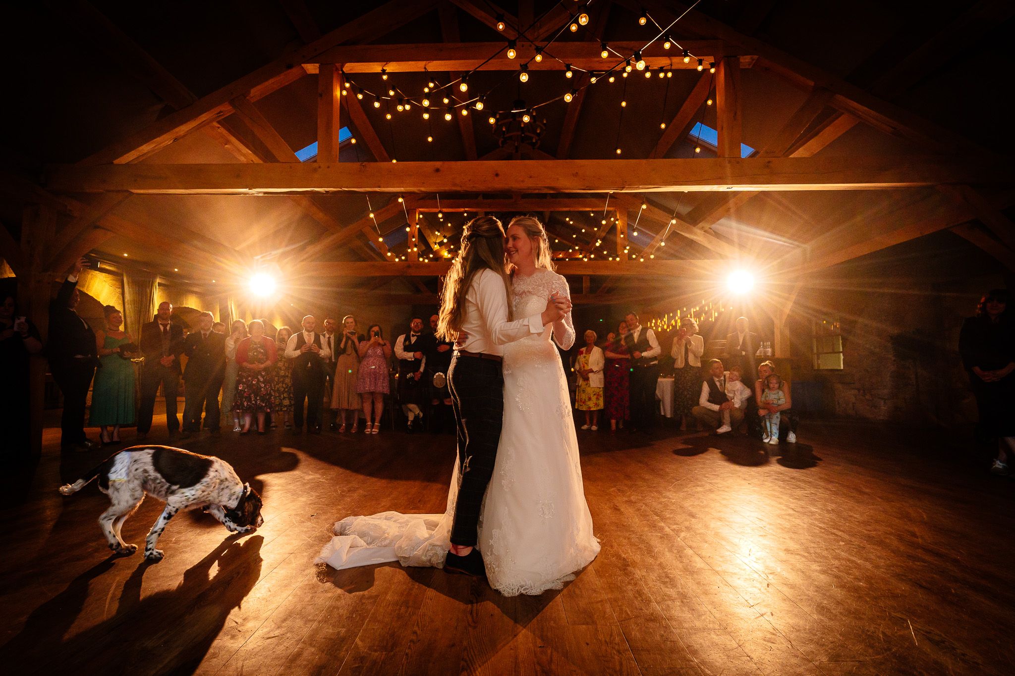 Warm glowing dance floor scene at an evening wedding reception with string lights overhead. Doxford Barns