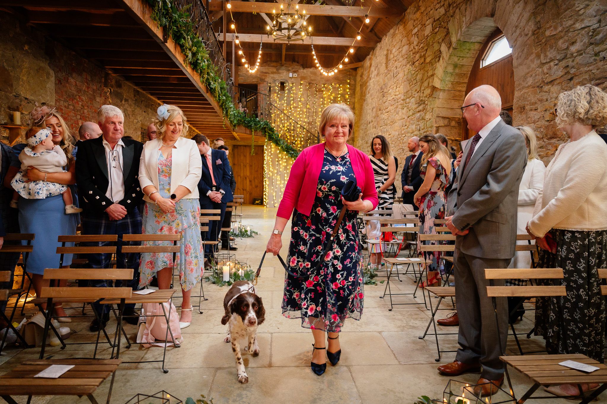 Wedding guests mingling inside a rustic stone barn reception venue. Doxford Barns