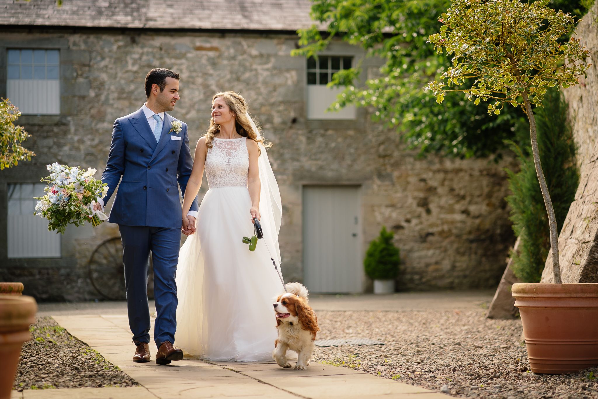 Garden pathway at stone venue with potted plants and wedding guests. Doxford Barns
