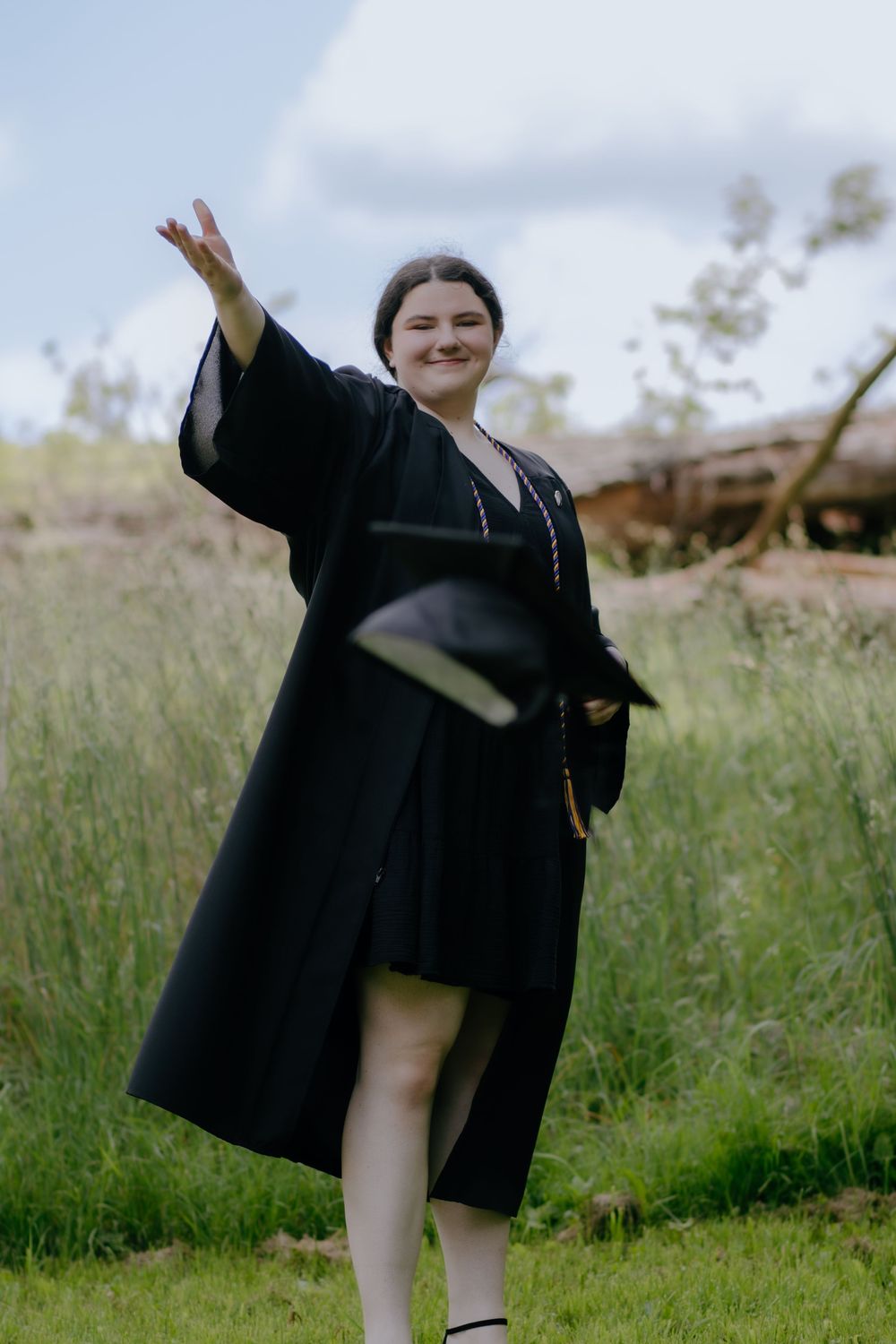 Graduate holding decorated mortarboard cap during outdoor photo session.