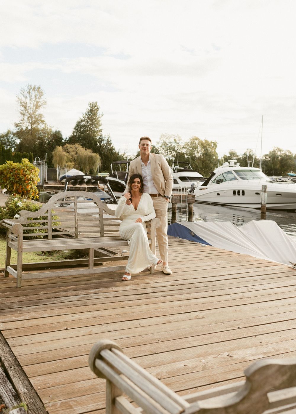 Wooden deck overlooking a marina with boats docked in the background on a sunny day.