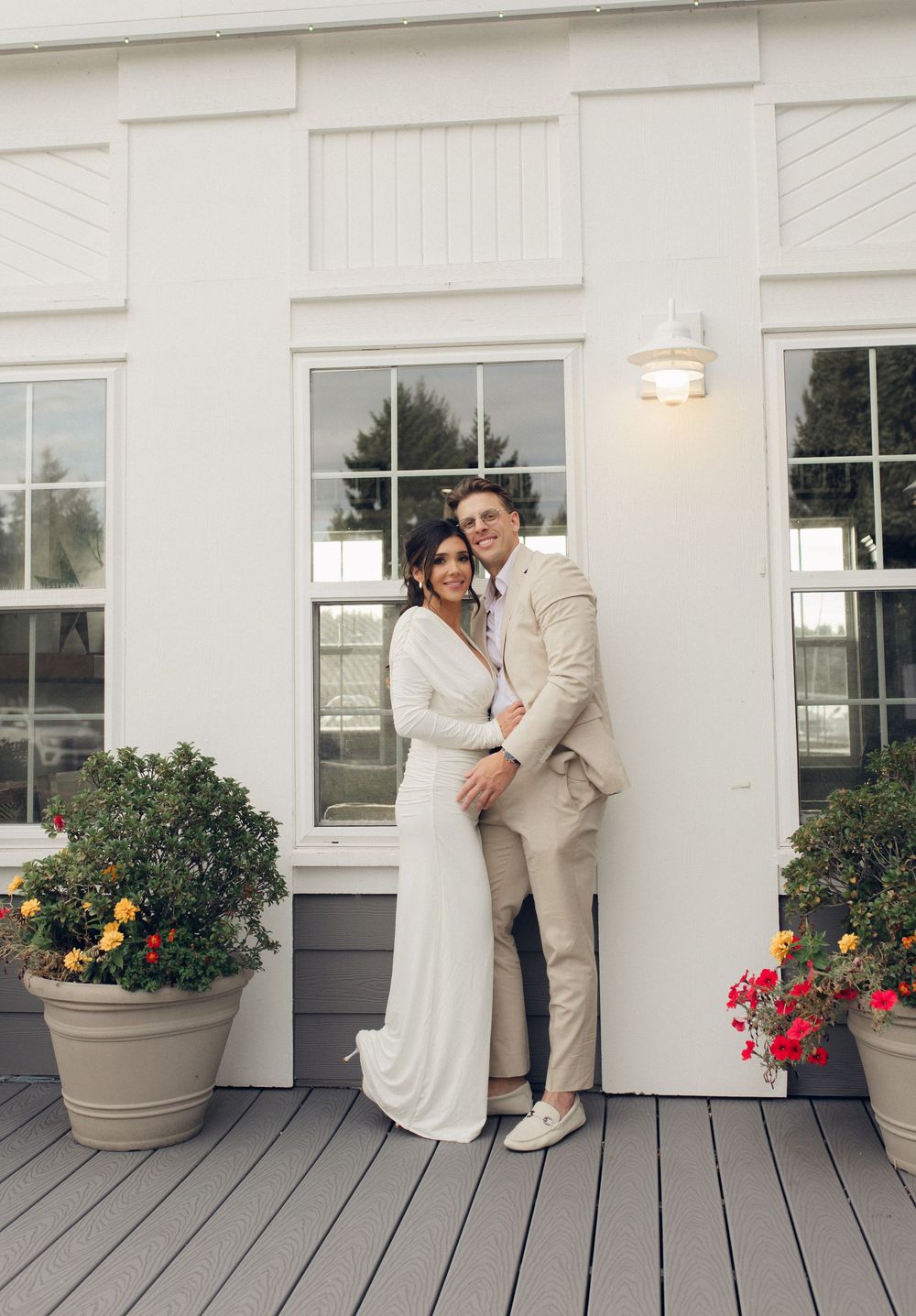 A romantic moment captured on a white deck with potted flowers and classic architecture.