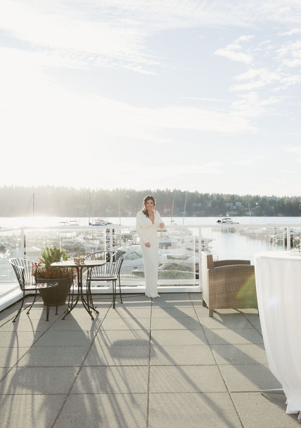 A scenic waterfront deck with outdoor furniture and a bright misty view over the marina.