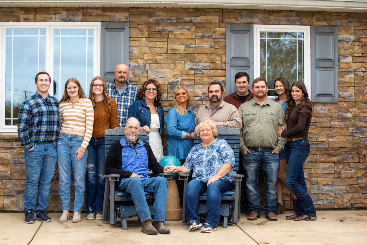Group poses together outdoors during autumn with golden fall foliage in background.