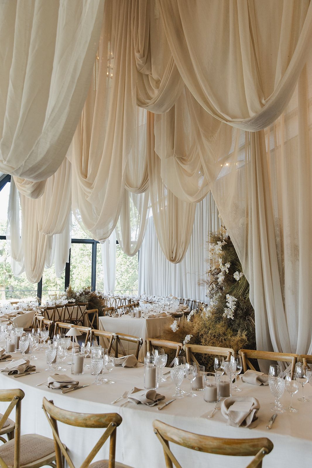 Wedding ceremony interior with orchids, draping, and soft neutral tones.