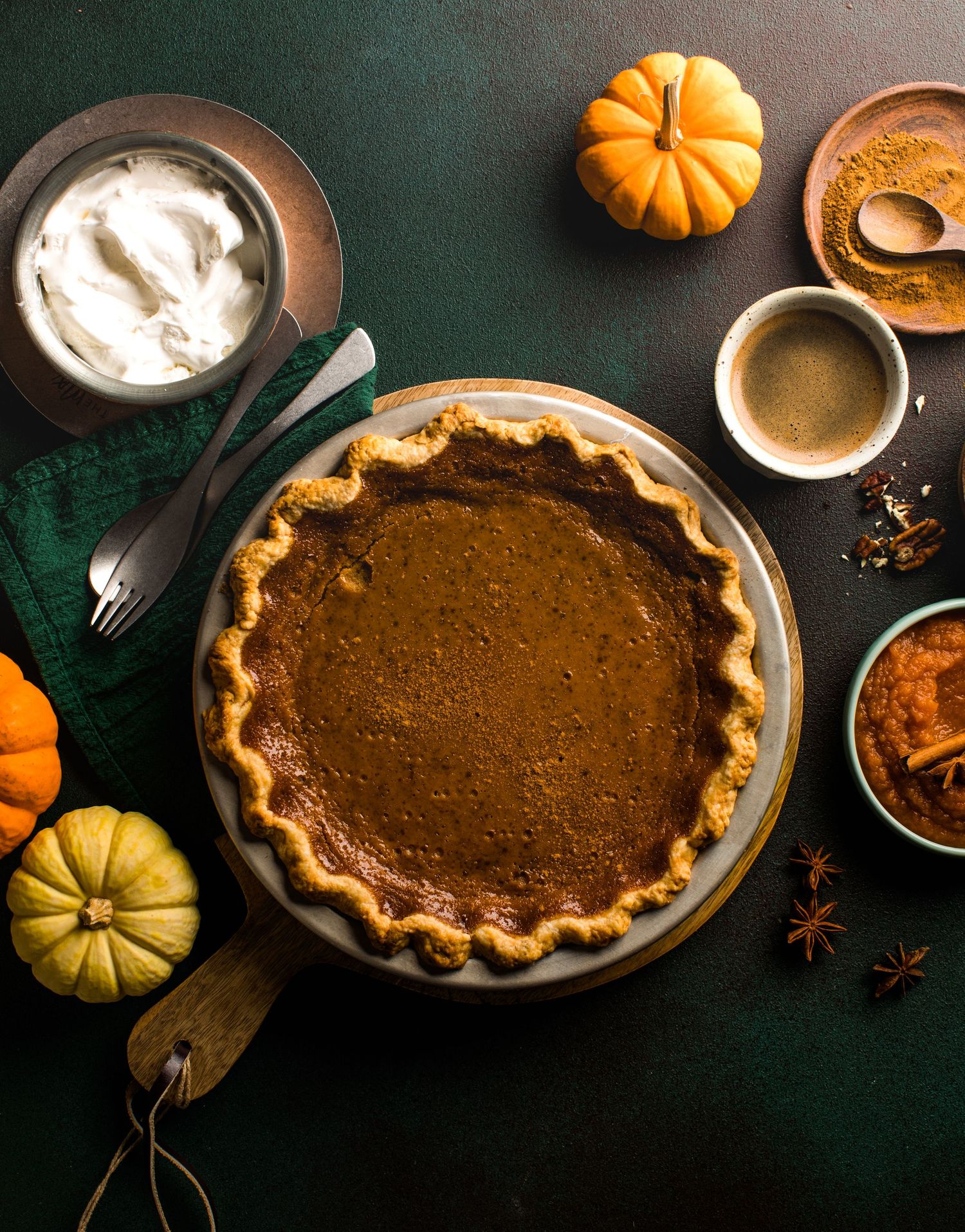 Freshly baked pumpkin pies with spices and small decorative gourds on a dark rustic background for Thanksgiving.